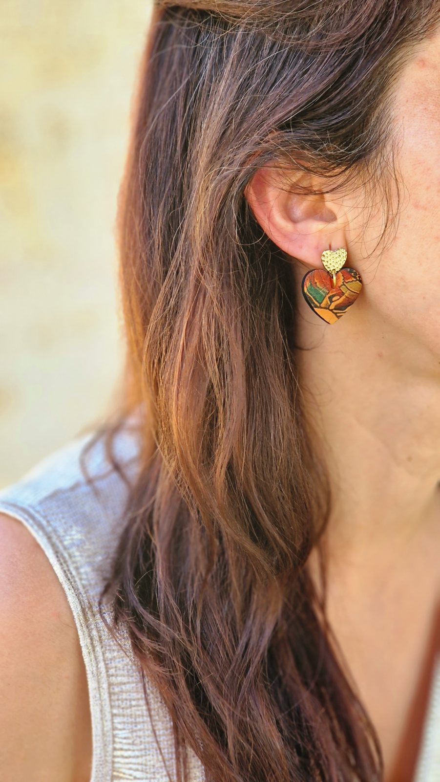 boucles d'oreilles en cuir effet tatouage en forme de coeur portées par une femme